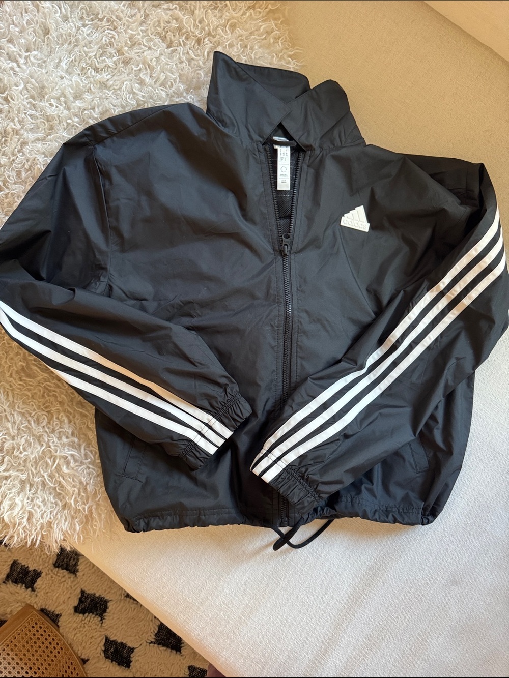 NWOT Adidas size small Black Windbreaker with White Three-Stripe Sleeves.